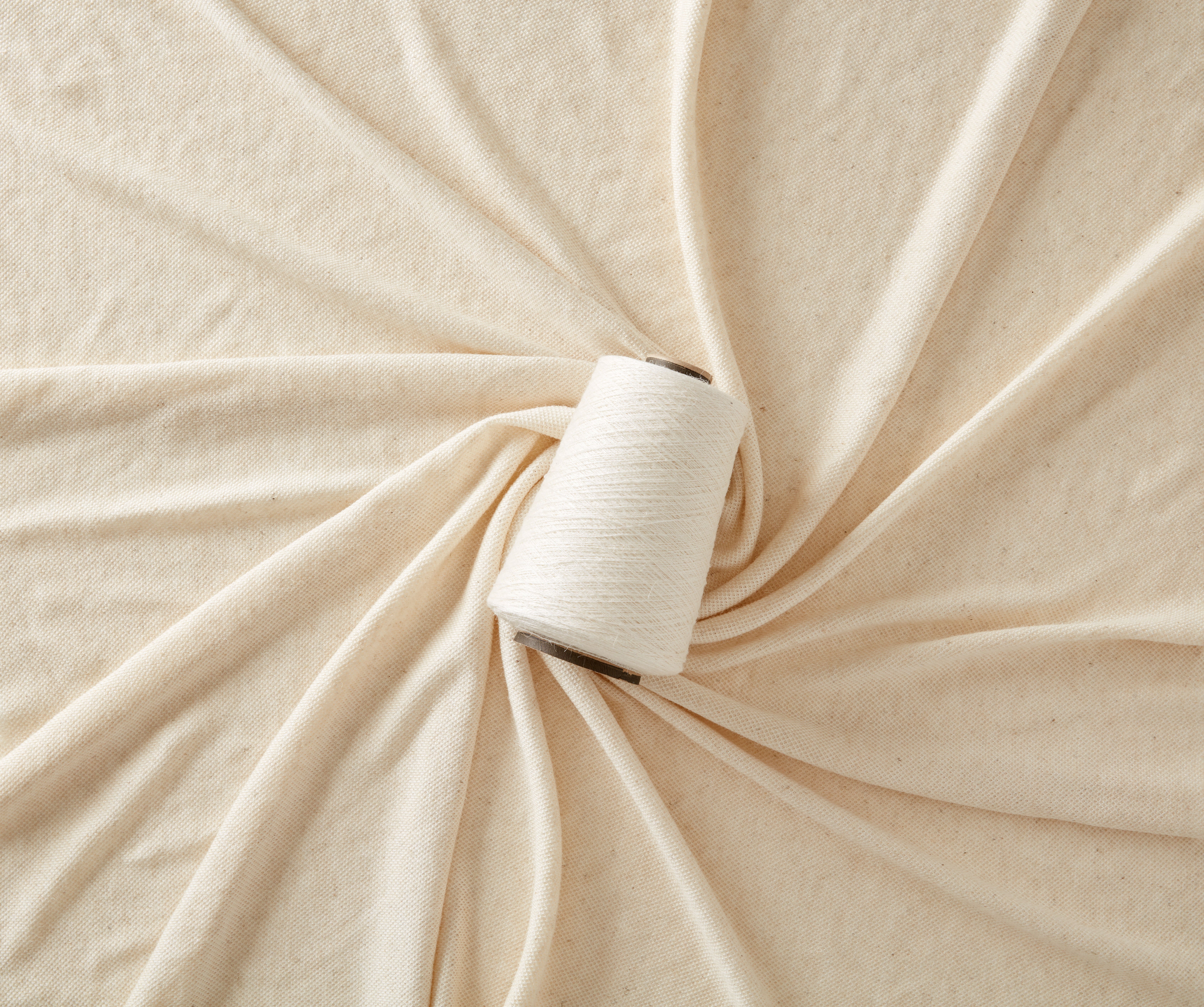 A spool of Piñayarn® on a bed of cream fabric A spool of Piñayarn® on a bed of cream fabric